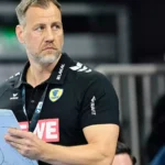 Maik Machulla steht mit Klemmbrett am Spielfeldrand in schwarzem Rhein-Neckar-Löwen-Poloshirt.