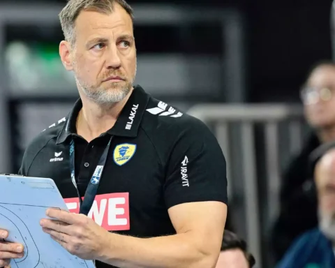Maik Machulla steht mit Klemmbrett am Spielfeldrand in schwarzem Rhein-Neckar-Löwen-Poloshirt.