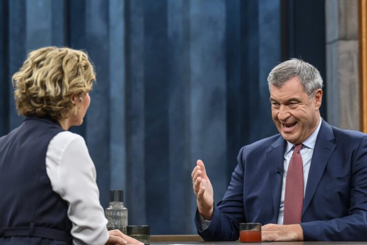 Markus Söder sitzt in einer TV-Sendung im Studio und spricht mit einer Moderatorin.