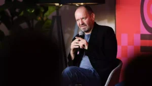 Philippe Sands sitzt mit einem Mikrofon auf einer Bühne bei einer Veranstaltung.