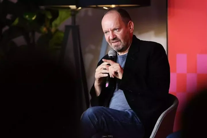 Philippe Sands sitzt mit einem Mikrofon auf einer Bühne bei einer Veranstaltung.