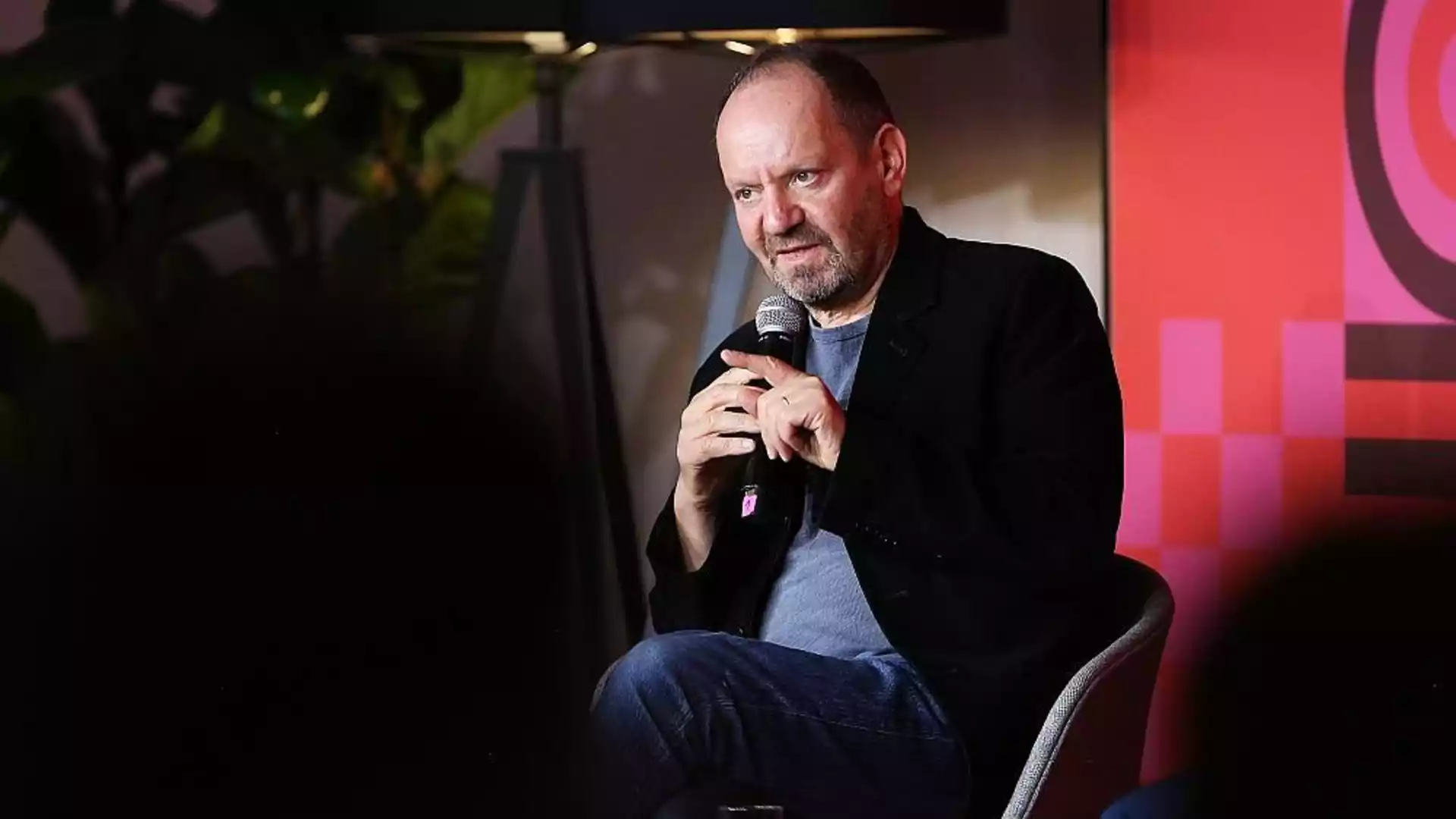 Philippe Sands sitzt mit einem Mikrofon auf einer Bühne bei einer Veranstaltung.