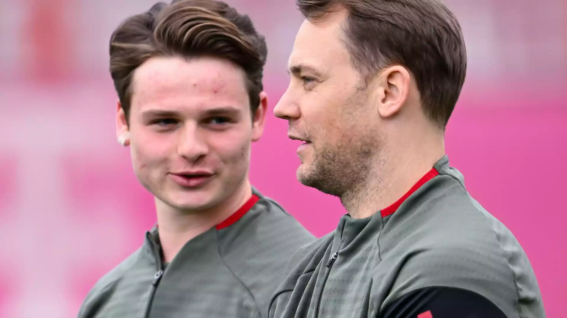 FC Bayern reist früh nach Stavanger und lässt Torwartfrage offen 1 Zwei Fußballspieler im Training in grauen Oberteilen vor pinkem Hintergrund, einer im Profil, der andere blickt nach vorn.