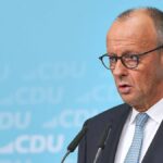Ein CDU-Politiker spricht bei einer Pressekonferenz vor blauem CDU-Hintergrund.