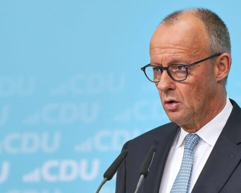 Ein CDU-Politiker spricht bei einer Pressekonferenz vor blauem CDU-Hintergrund.