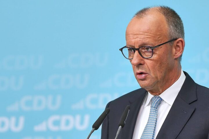 Ein CDU-Politiker spricht bei einer Pressekonferenz vor blauem CDU-Hintergrund.