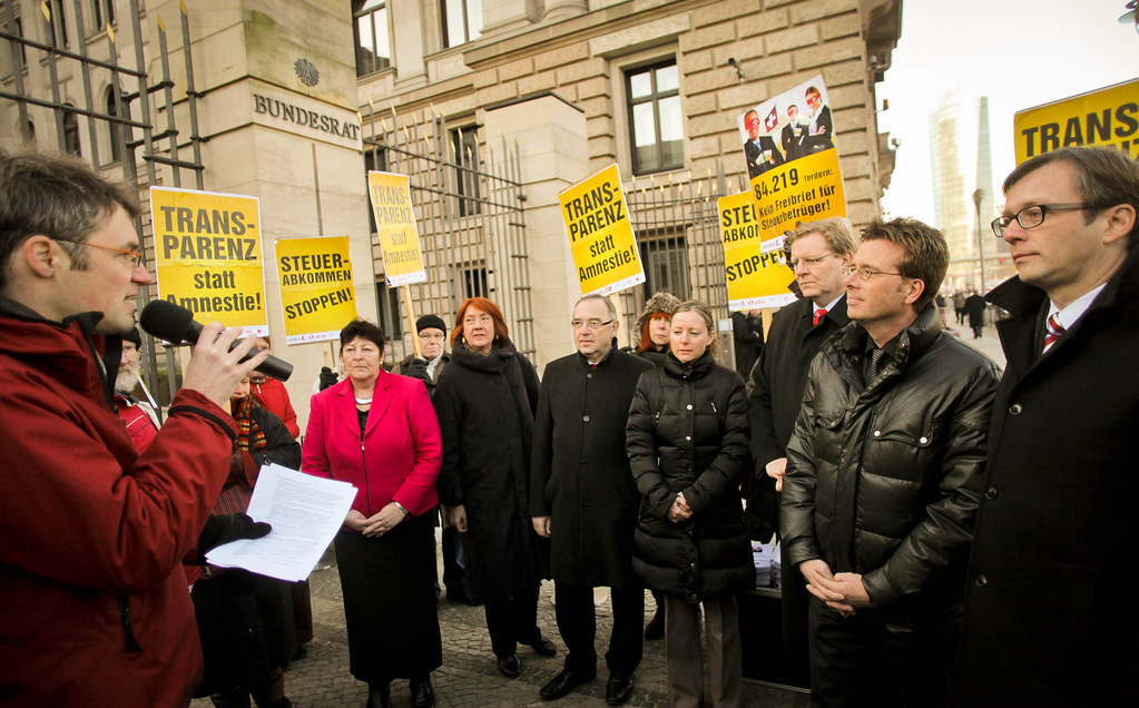 Menschen stehen vor dem Bundesrat in Berlin bei einer Protest- oder Kundgebungsaktion mit gelben Transparenten.