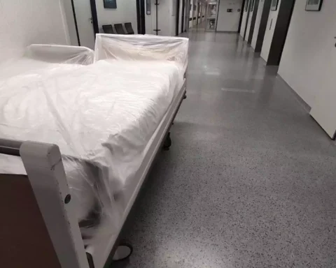 Ein Bett mit Schutzfolie steht in einem Krankenhausflur.