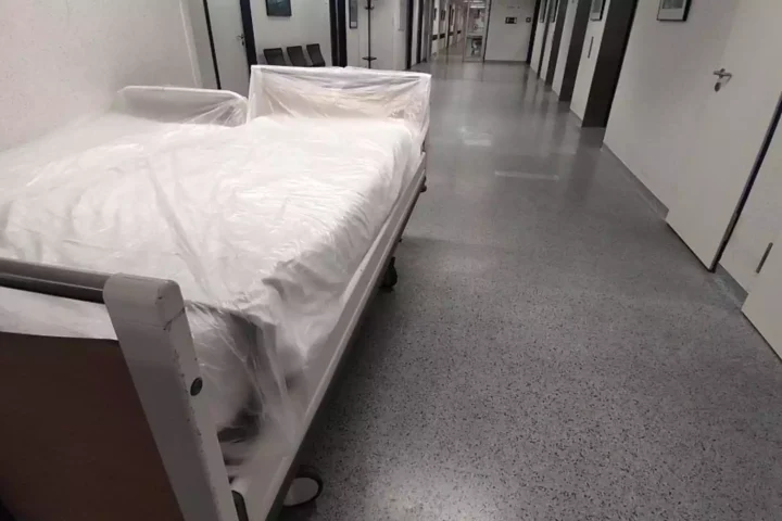 Ein Bett mit Schutzfolie steht in einem Krankenhausflur.