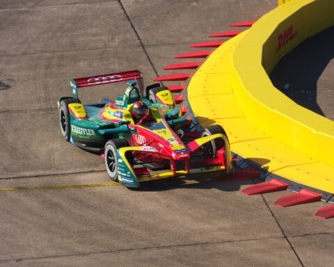 Formel-E-Rennwagen mit Schaeffler-Branding fährt auf einer Rennstrecke an einer gelben Barriere vorbei.