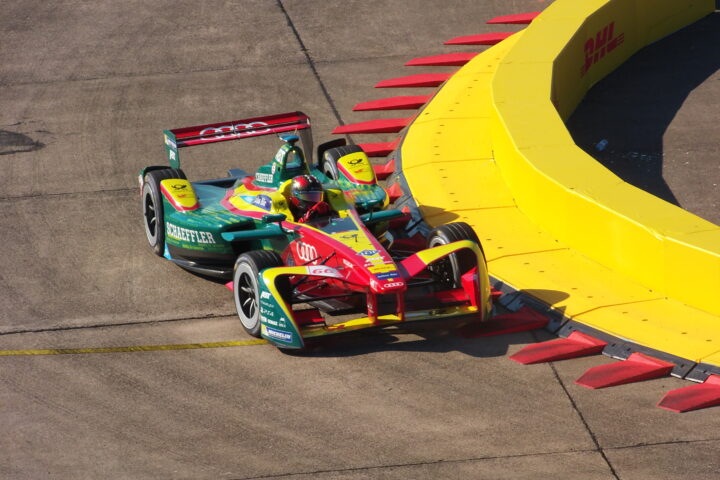 Formel-E-Rennwagen mit Schaeffler-Branding fährt auf einer Rennstrecke an einer gelben Barriere vorbei.