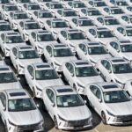 Reihen dicht geparkter weißer BYD-Hybridautos auf einem Abstellplatz.