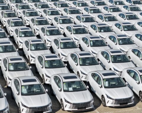 Reihen dicht geparkter weißer BYD-Hybridautos auf einem Abstellplatz.