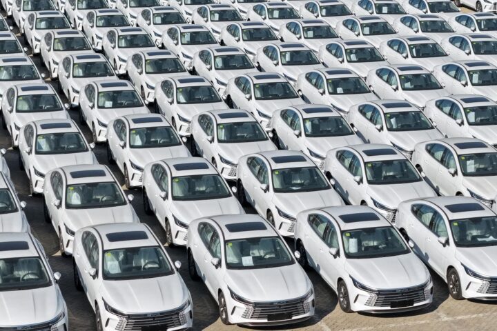 Reihen dicht geparkter weißer BYD-Hybridautos auf einem Abstellplatz.