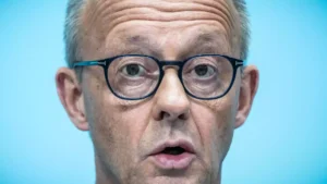 Nahaufnahme von Friedrich Merz mit Brille vor blauem Hintergrund