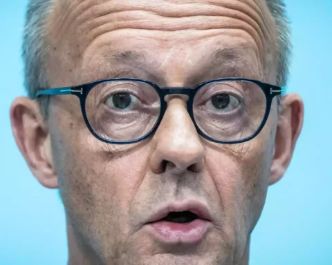 Nahaufnahme von Friedrich Merz mit Brille vor blauem Hintergrund