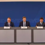 Lars Klingbeil sitzt bei einer Pressekonferenz des Bundesfinanzministeriums am Tisch mit weiteren Teilnehmern.