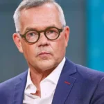 Michael Roth in einem Studio-Porträt mit Brille und blauem Sakko.