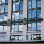Fassade eines modernen Gebäudes mit großen Fenstern und dekorativem Metall-Element.