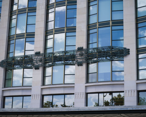 Fassade eines modernen Gebäudes mit großen Fenstern und dekorativem Metall-Element.