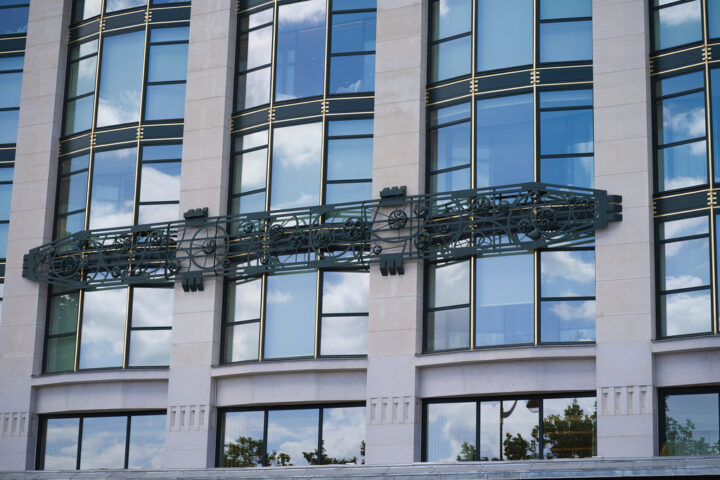 Fassade eines modernen Gebäudes mit großen Fenstern und dekorativem Metall-Element.