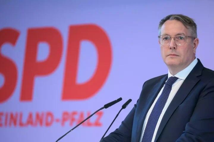 Alexander Schweitzer steht vor einem SPD-Hintergrund an einem Rednerpult.