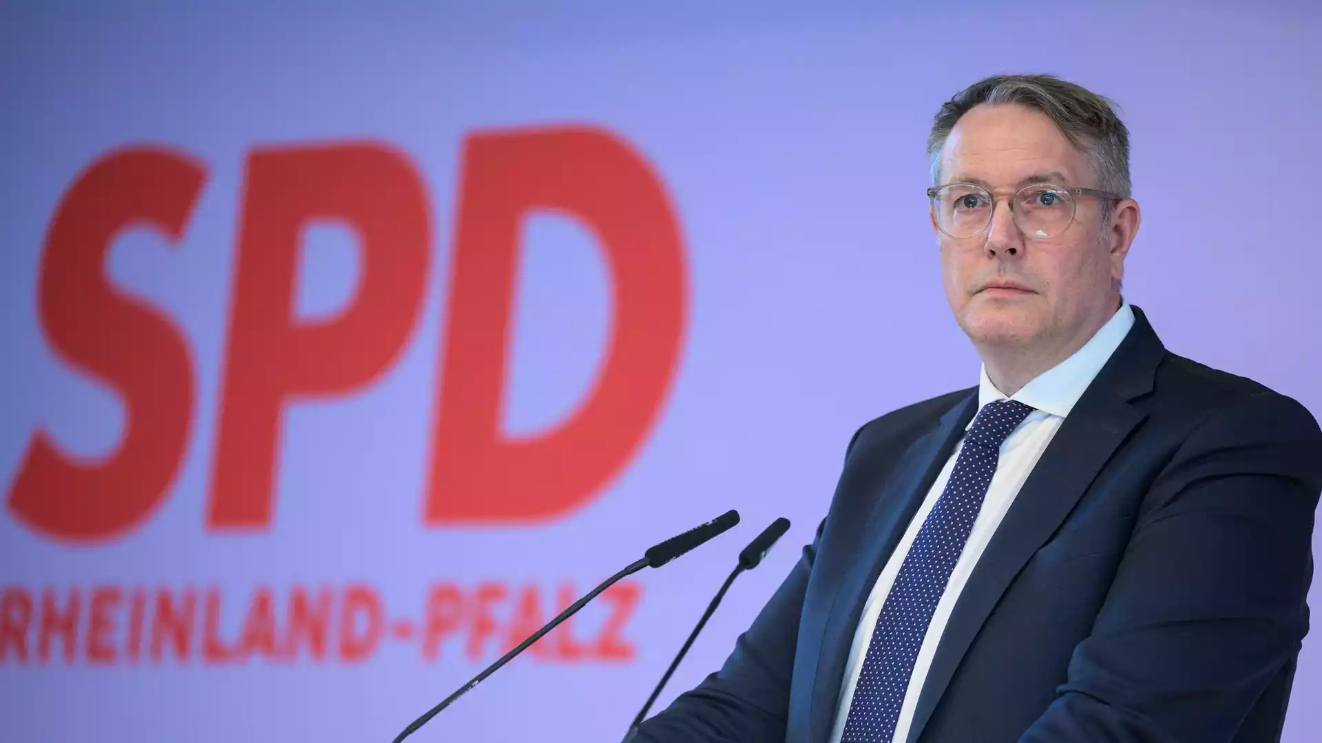 Alexander Schweitzer steht vor einem SPD-Hintergrund an einem Rednerpult.