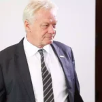 Alois Rainer im dunklen Anzug und mit gestreifter Krawatte vor hellem Hintergrund.