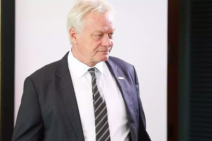 Alois Rainer im dunklen Anzug und mit gestreifter Krawatte vor hellem Hintergrund.