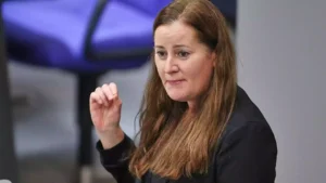 Janine Wissler spricht bei einer Veranstaltung und hebt die Hand leicht an.