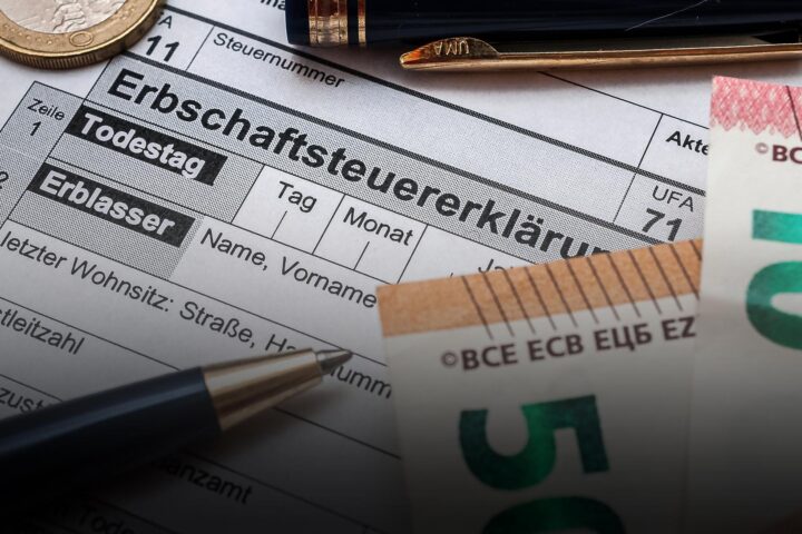 Nahaufnahme eines deutschen Formulars zur Erbschaftsteuer mit Münze, Stift und Euro-Banknoten.