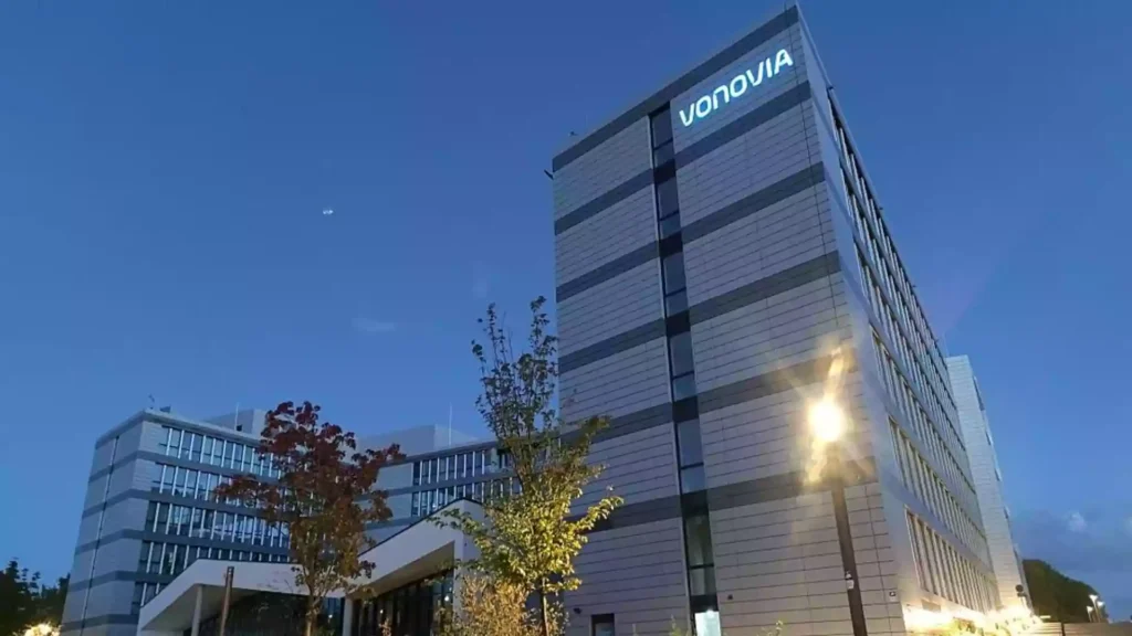 Vonovia-Verwaltungsgebäude bei Dämmerung mit beleuchtetem Logo an der Fassade.
