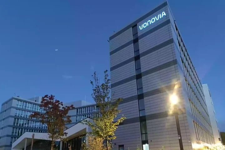 Vonovia-Verwaltungsgebäude bei Dämmerung mit beleuchtetem Logo an der Fassade.