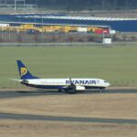 Ryanair-Flugzeug rollt auf einem Flughafengelände vor einem Logistikgebäude mit DACHSER-Schriftzug.