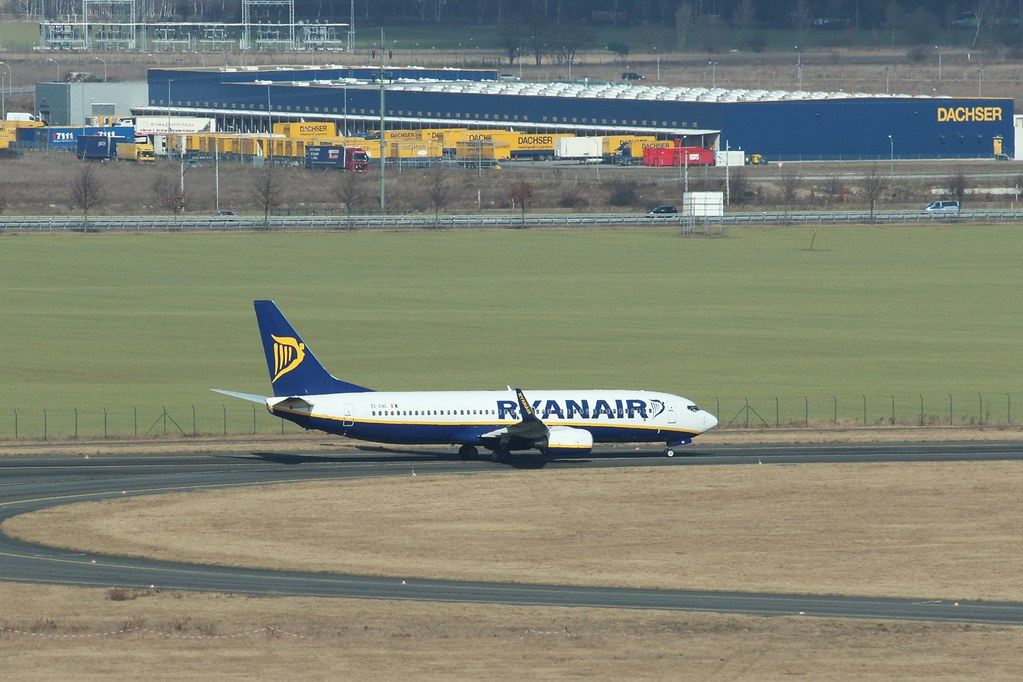 Ryanair-Flugzeug rollt auf einem Flughafengelände vor einem Logistikgebäude mit DACHSER-Schriftzug.