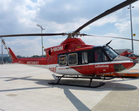 Roter Rettungshubschrauber steht auf dem Vorfeld eines Flughafens.