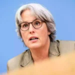 Kerstin Claus spricht vor blauem Hintergrund bei einer Pressekonferenz.