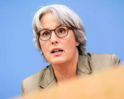 Kerstin Claus spricht vor blauem Hintergrund bei einer Pressekonferenz.