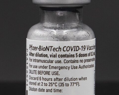 Eine Vial mit der Aufschrift Pfizer-BioNTech COVID-19 Vaccine vor dunklem Hintergrund.