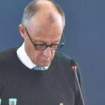 Friedrich Merz blickt bei einer politischen Sitzung nach unten, vor ihm steht ein Mikrofon.