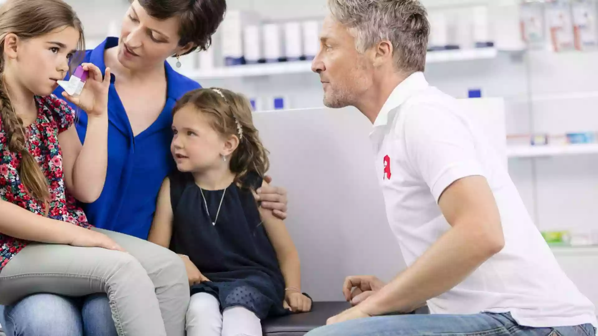 Ein Apotheker berät eine Frau mit zwei Kindern in einer Apotheke.