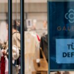 Galeria-Schaufenster mit Modepuppen und Schild „Tür defekt“.