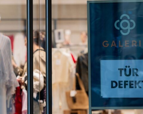 Galeria-Schaufenster mit Modepuppen und Schild „Tür defekt“.