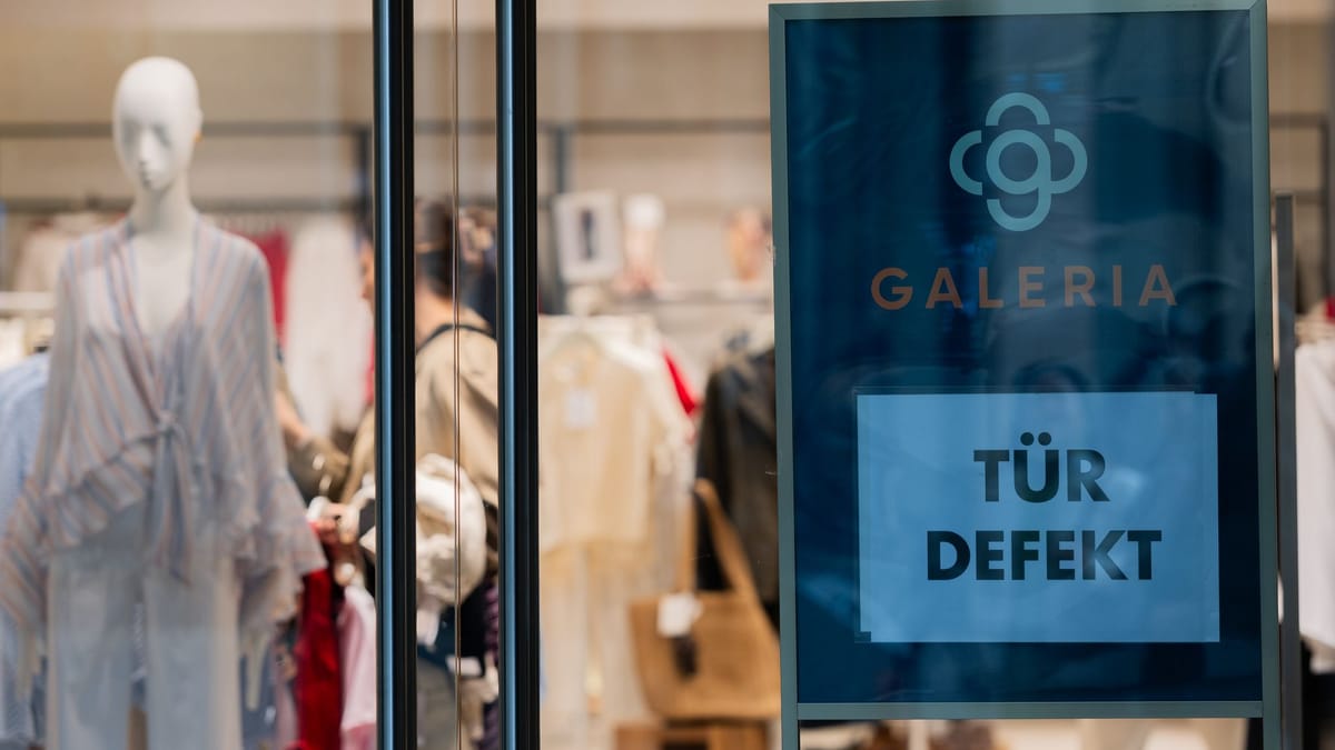 Galeria-Schaufenster mit Modepuppen und Schild „Tür defekt“.