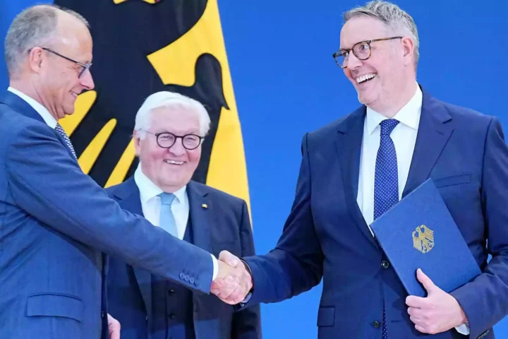Alexander Schweitzer schüttelt in Berlin einem Mann im Anzug die Hand, während ein weiterer Politiker daneben lächelt.