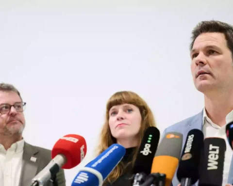 Drei Politiker stehen vor mehreren Mikrofonen bei einer Pressekonferenz.