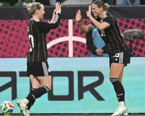 Zwei deutsche Fußballerinnen in schwarzen DFB-Trikots klatschen sich auf dem Spielfeld ab.
