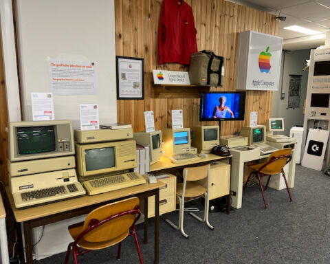 Ausstellung mit mehreren alten Apple-Computern und Apple-Logo an der Wand.