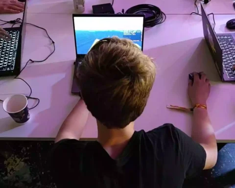 Jugendliche sitzen an Laptops an einem Tisch und nutzen Computer.