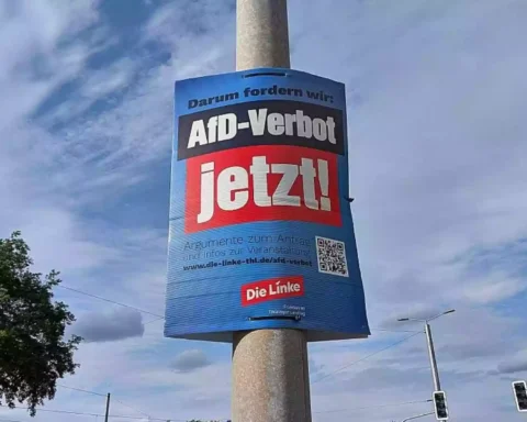 Plakat mit der Aufschrift „AfD-Verbot jetzt!“ an einem Laternenmast im Straßenraum.